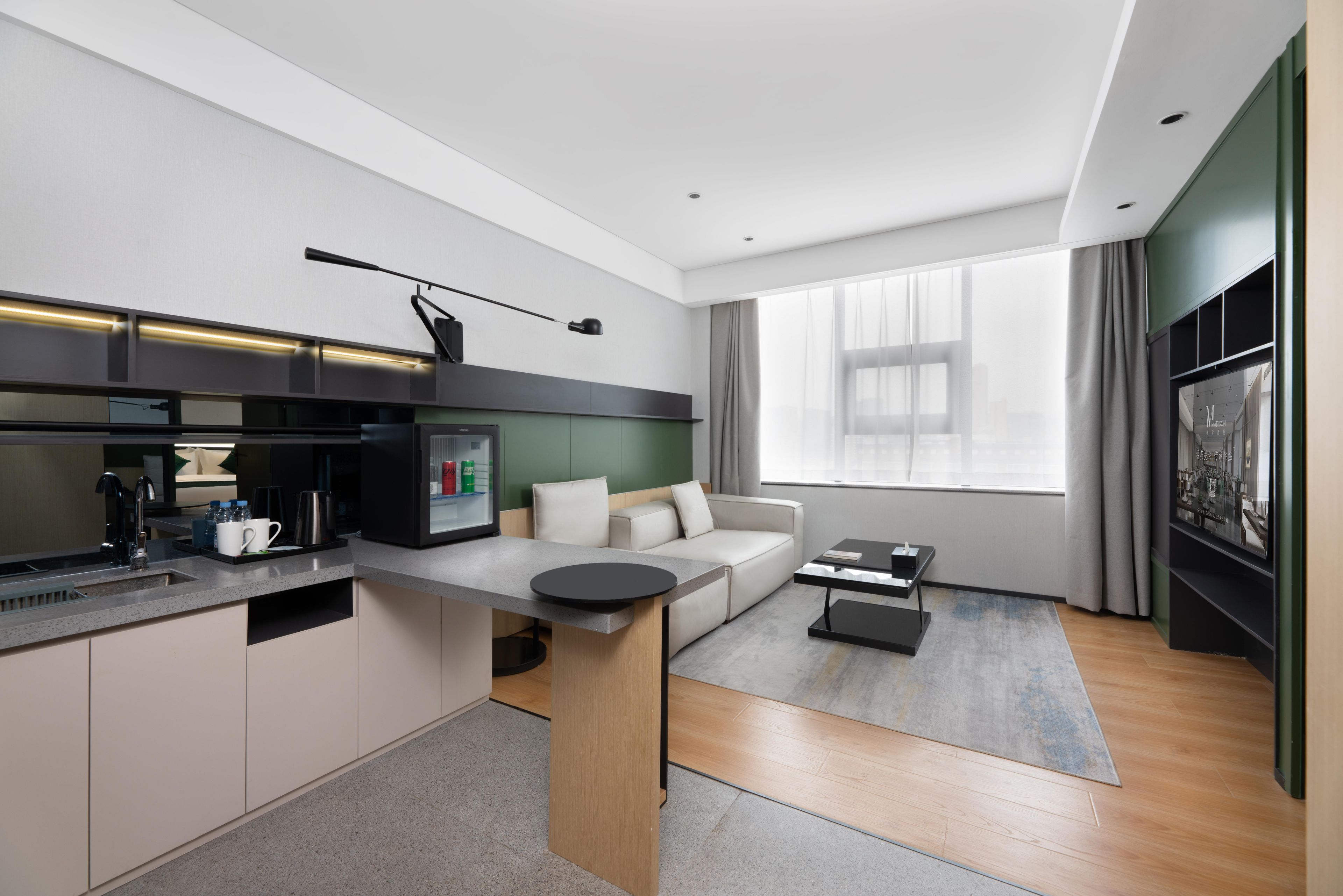 A modern kitchen with a built-in stove, a dining area with a sofa, and a large window with curtains.