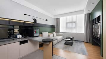 Una cocina moderna con estufa integrada, un área de comedor con sofá y un amplio ventanal con cortinas.