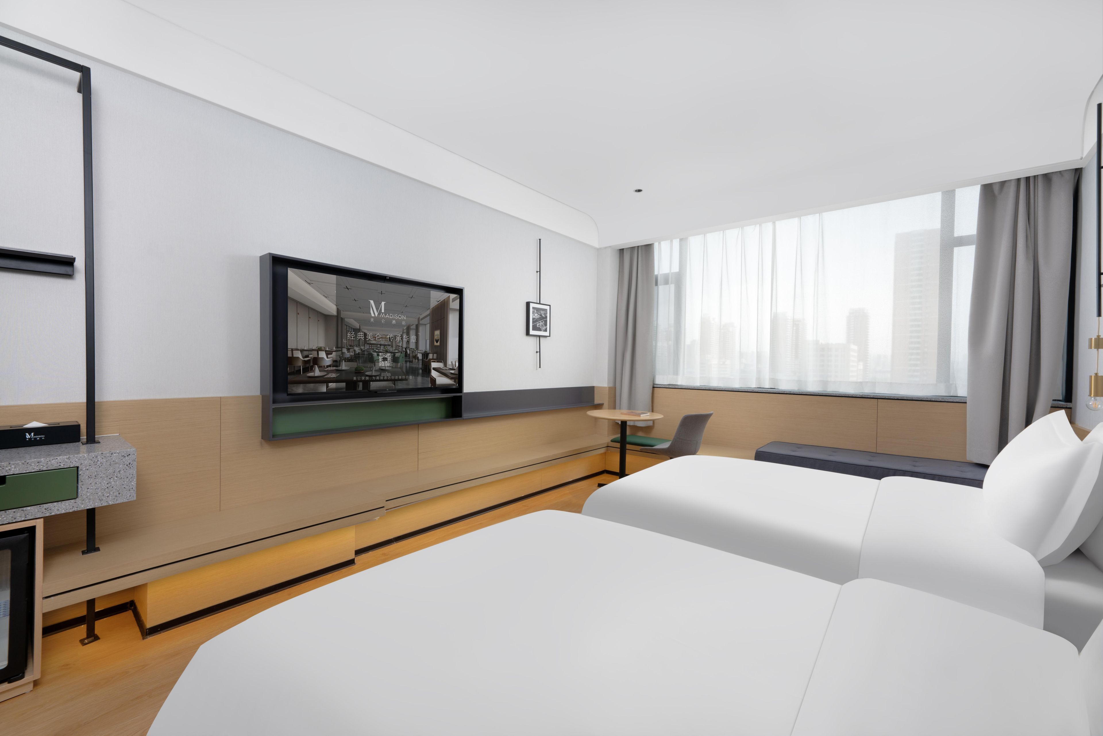 A modern hotel room with a large bed, a TV mounted on the wall, a small table, and a window with curtains.