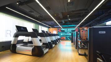 A gym with treadmills, exercise equipment, and a digital display.