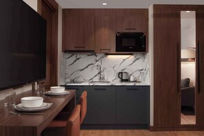 A modern kitchen with dark wood cabinets, a marble backsplash, and a built-in microwave. - Residence Inn By Marriott Trabzon (Trabzon)