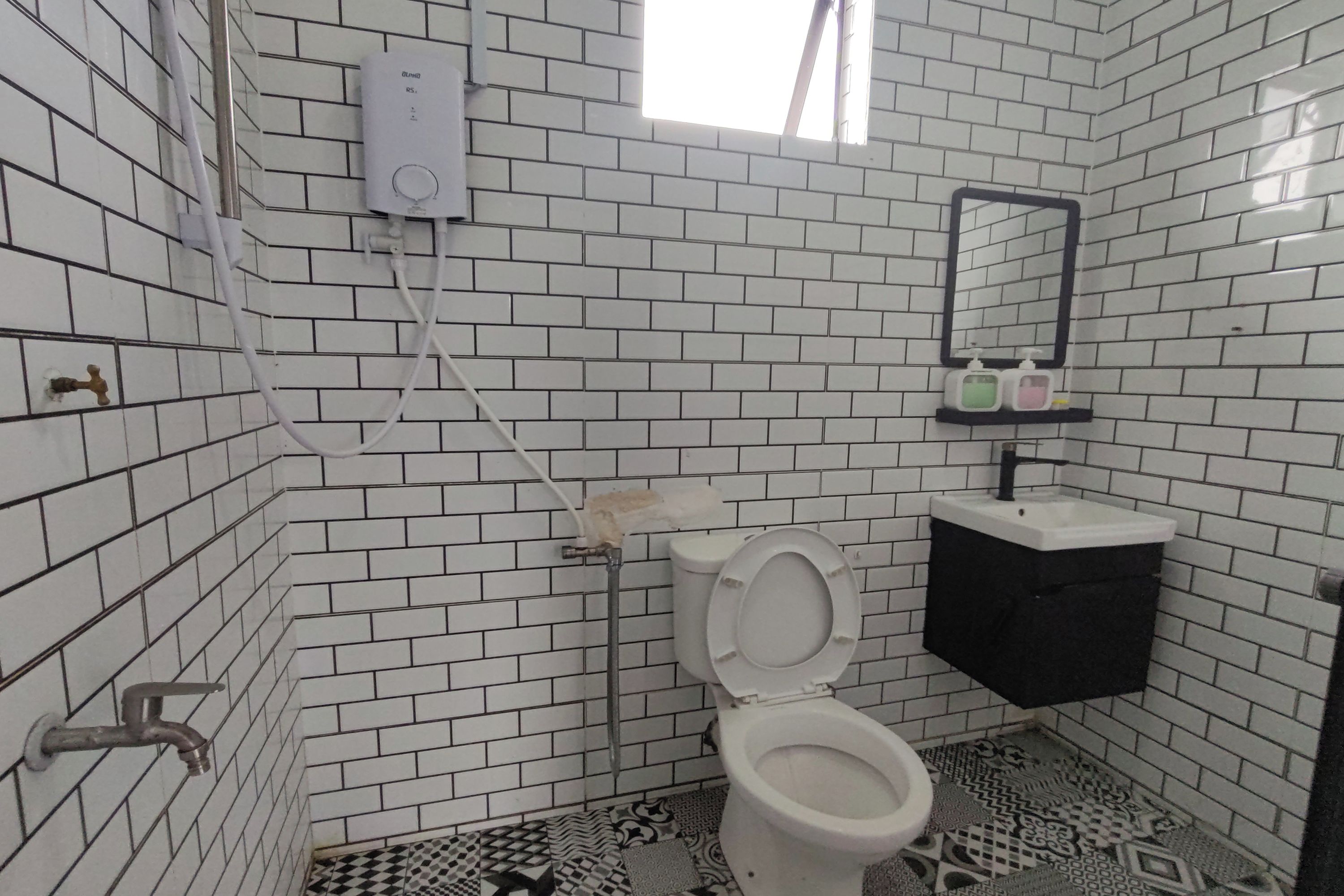 A bathroom with white tiled walls, a toilet, a sink, and a mirror.