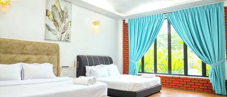 A hotel room with two beds, a ceiling fan, a large window with curtains, and a brick wall.