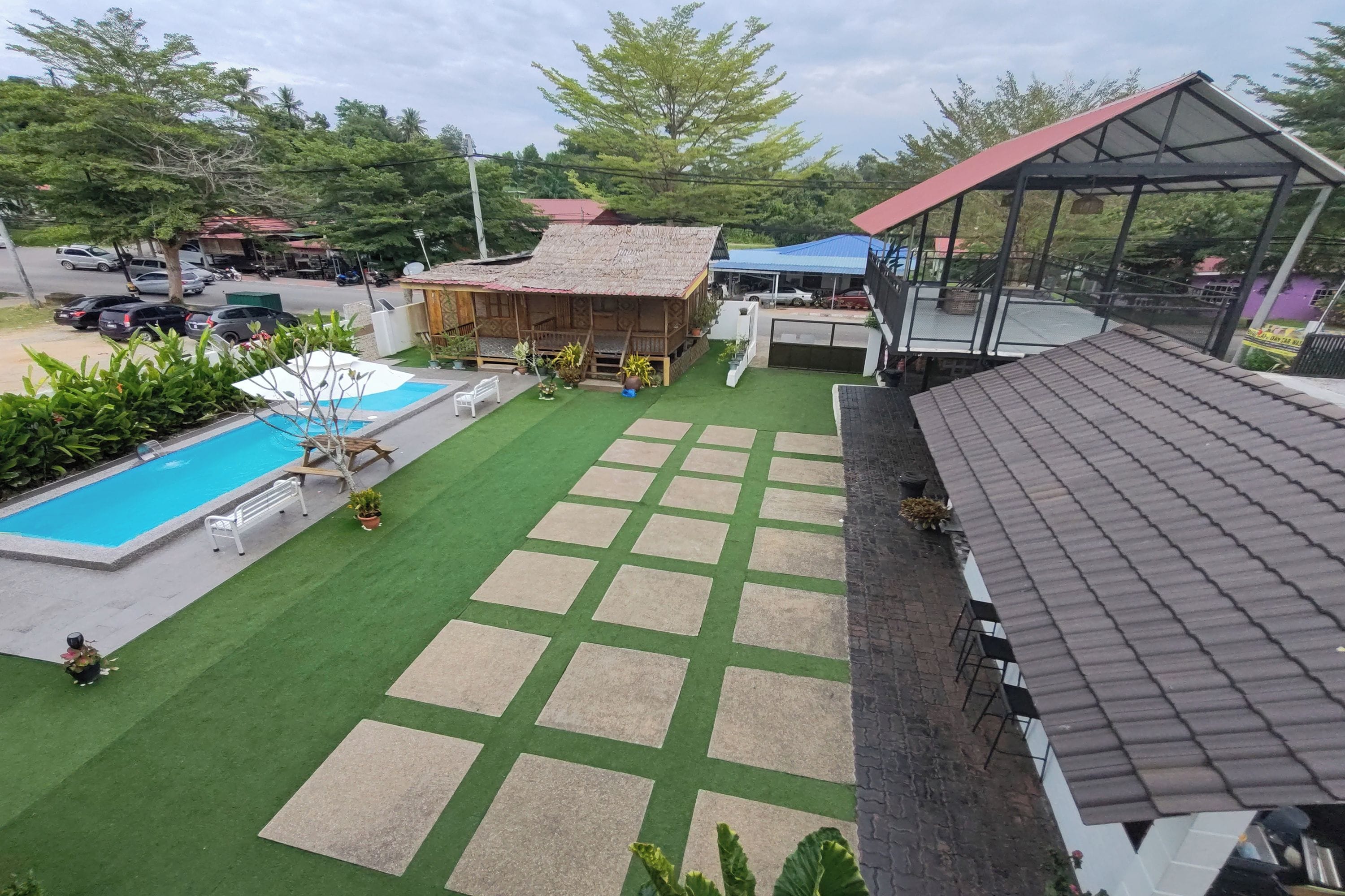 A hotel with a swimming pool, a covered outdoor area, and a view of the surrounding landscape.