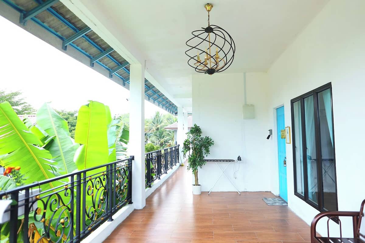 Un balcon abrité, agrémenté d’un pot de fleurs, d’un luminaire suspendu et offrant une vue sur la verdure.