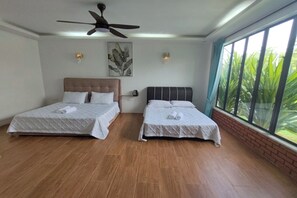 A hotel room with two beds, a ceiling fan, a large window with a view of greenery, and a brick wall. - Aeden Villa Roomstay & Homestay By Zuzu (Kuala Kangsar)