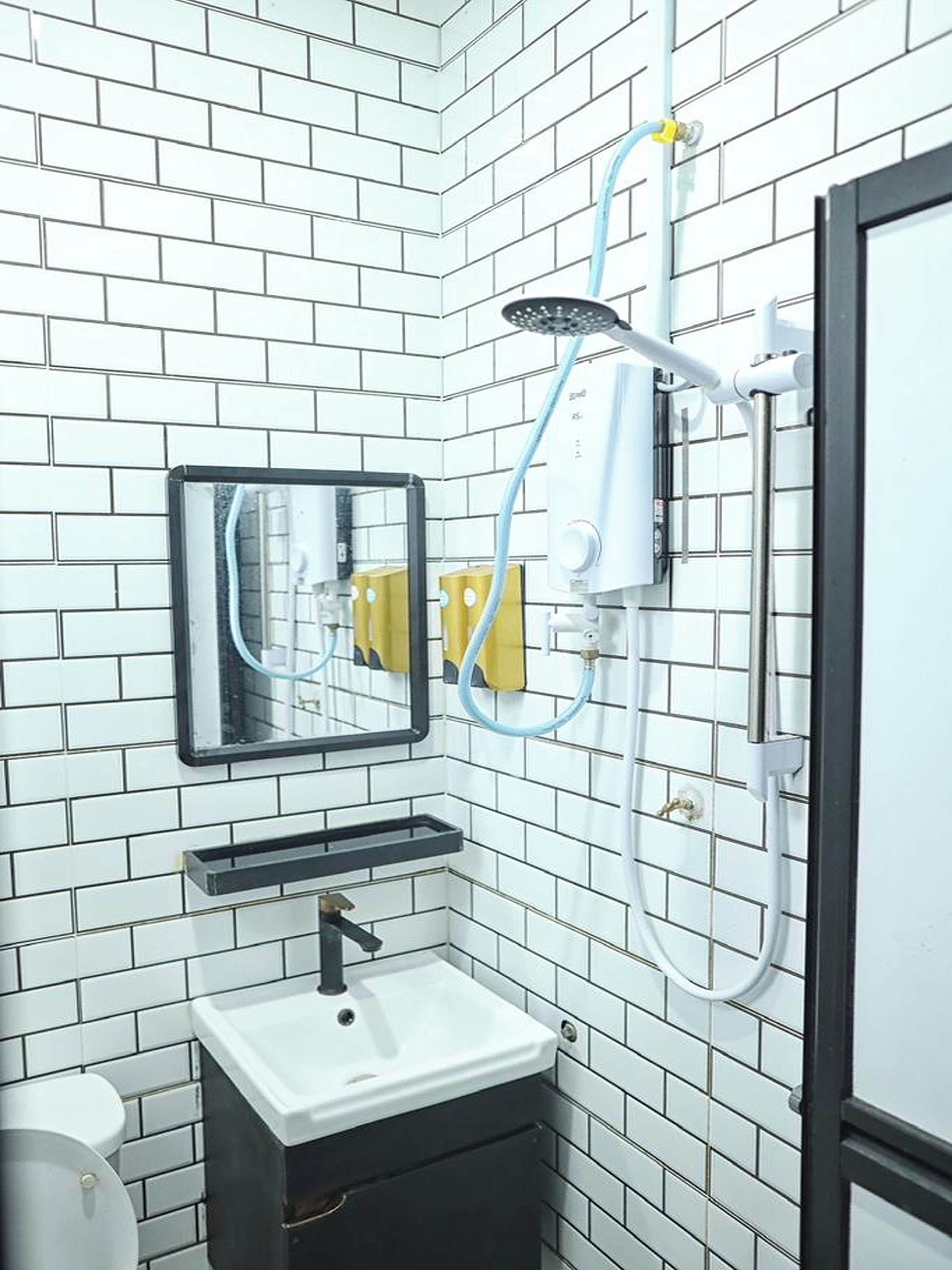 A bathroom with white tiled walls, a sink, a mirror, and a shower with a handheld showerhead.