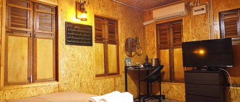 A room with a bed, a desk, a television, and wooden walls.