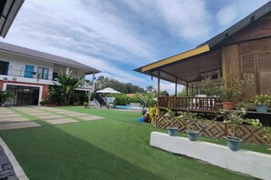 A courtyard with artificial grass, a wooden deck, potted plants, and a building with a tiled roof. - Aeden Villa Roomstay & Homestay By Zuzu (Kuala Kangsar)