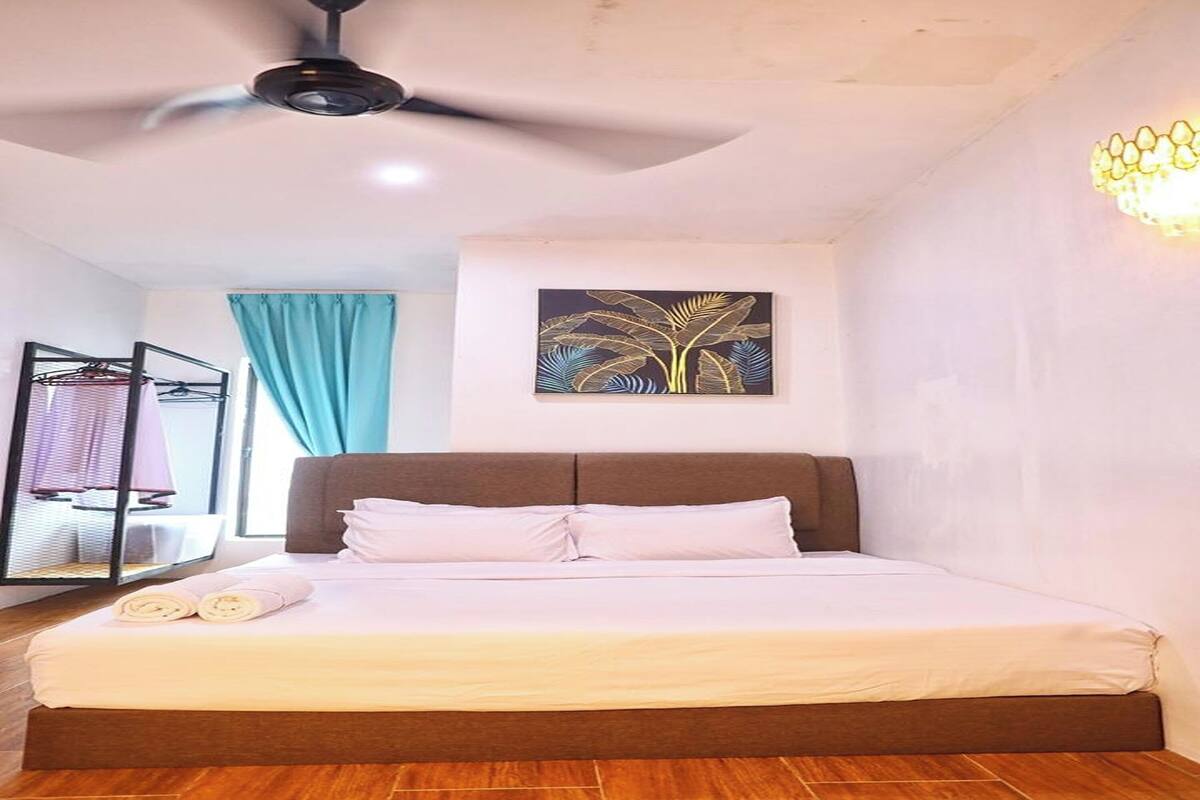 Une chambre à coucher avec un lit, un ventilateur de plafond, un luminaire fixé au mur et une fenêtre avec des rideaux.