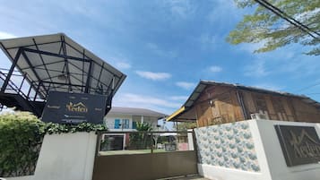 A villa with a large open space, a covered area, and a gated entrance.