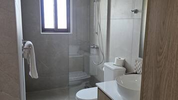 Un baño moderno con ducha acristalada, inodoro y lavamanos.