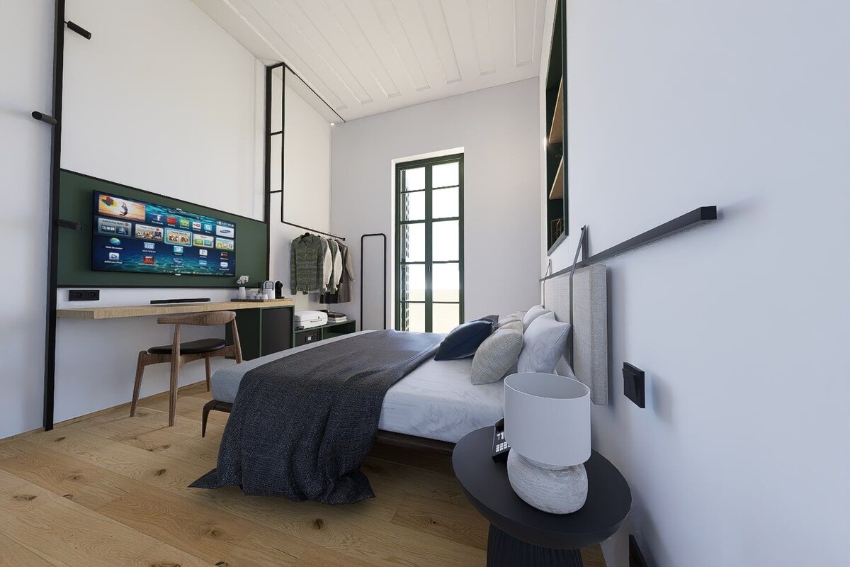 A modern bedroom with a bed, bedside table, and a desk with a computer.