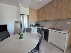 A modern kitchen with white cabinets, a stainless steel refrigerator, a built-in oven, a dishwasher, and a sink. - Kentrikon 1924 Boutique Hotel And Suites (Paphos)