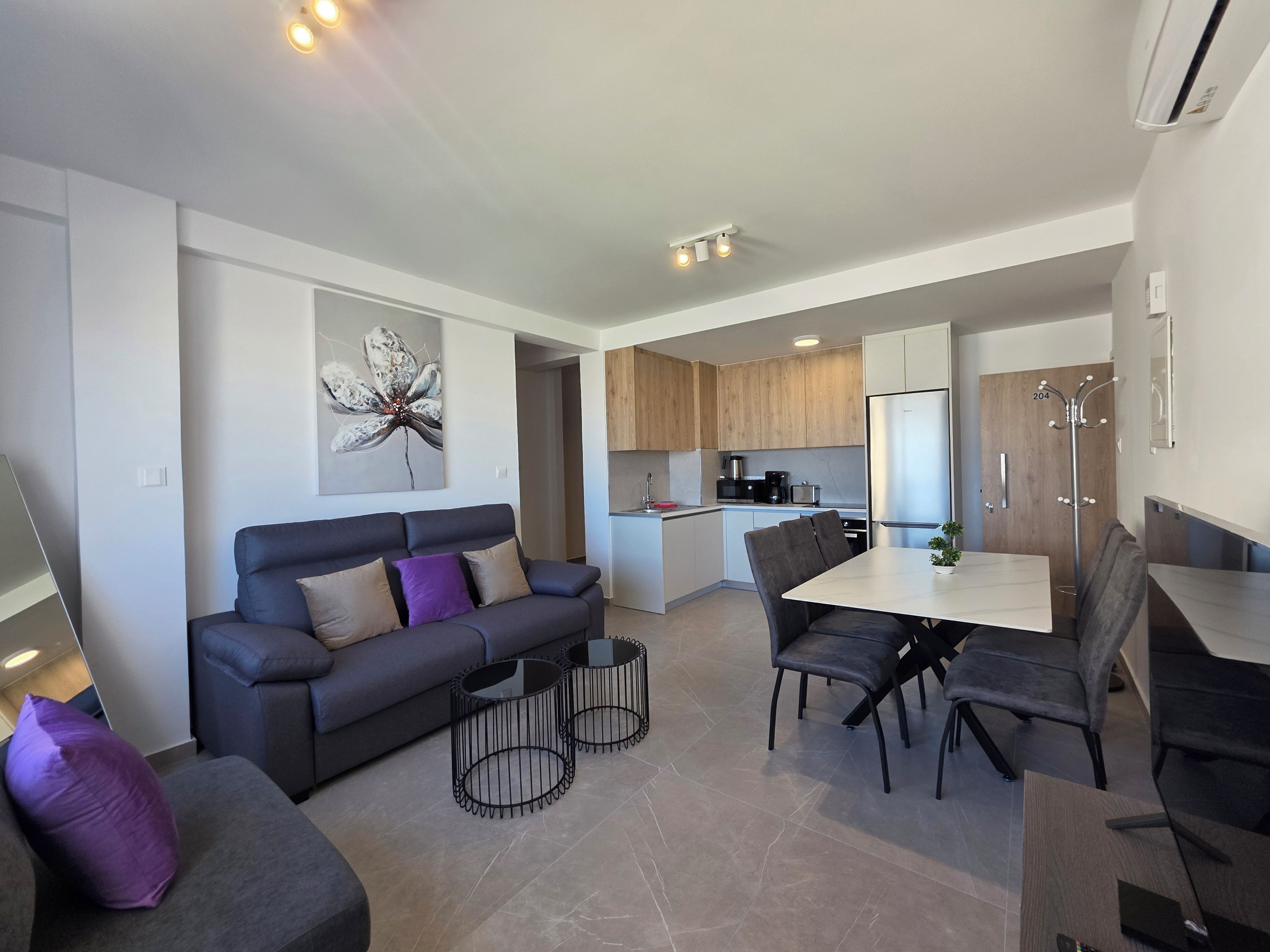 A modern living room with a sofa, coffee table, and dining table with chairs.