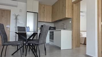 A modern kitchen with white cabinets, a central island, and a dining area with grey chairs.