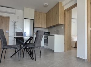 Una cocina moderna con armarios blancos, una isla central y una zona de comedor con sillas grises.