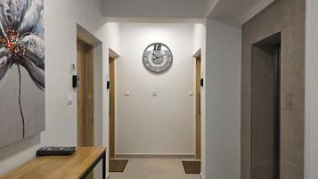 Un pasillo con un reloj, una mesa de madera y una puerta.
