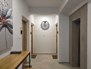 A hallway with a clock, a wooden table, and a door. - Kentrikon 1924 Boutique Hotel And Suites (Paphos)