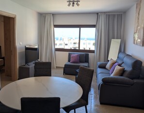 A modern living room with a sofa, a dining table, and a TV. - Kentrikon 1924 Boutique Hotel And Suites (Paphos)