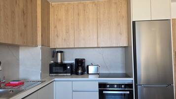 A modern kitchen with wooden cabinets, a Bosch microwave, a coffee maker, a stainless steel refrigerator, and a built-in oven.