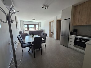 A modern kitchen with a built-in oven and a dining area with a table and chairs. - Kentrikon 1924 Boutique Hotel And Suites (Paphos)