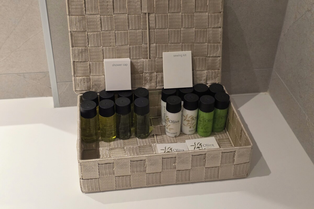 A wicker basket containing various bottles of olive oil and a sewing kit.