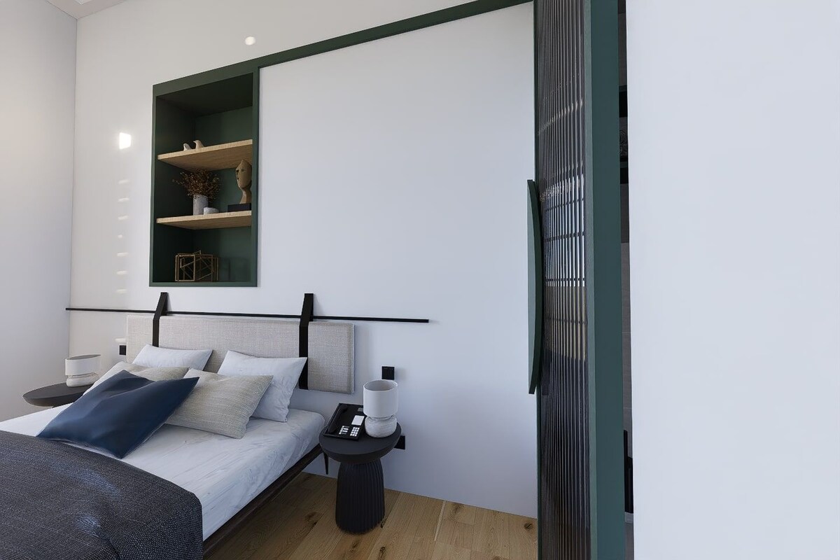 A modern bedroom with a bed, bedside tables, a nightstand, a mirror, and a built-in shelf with decorative items.