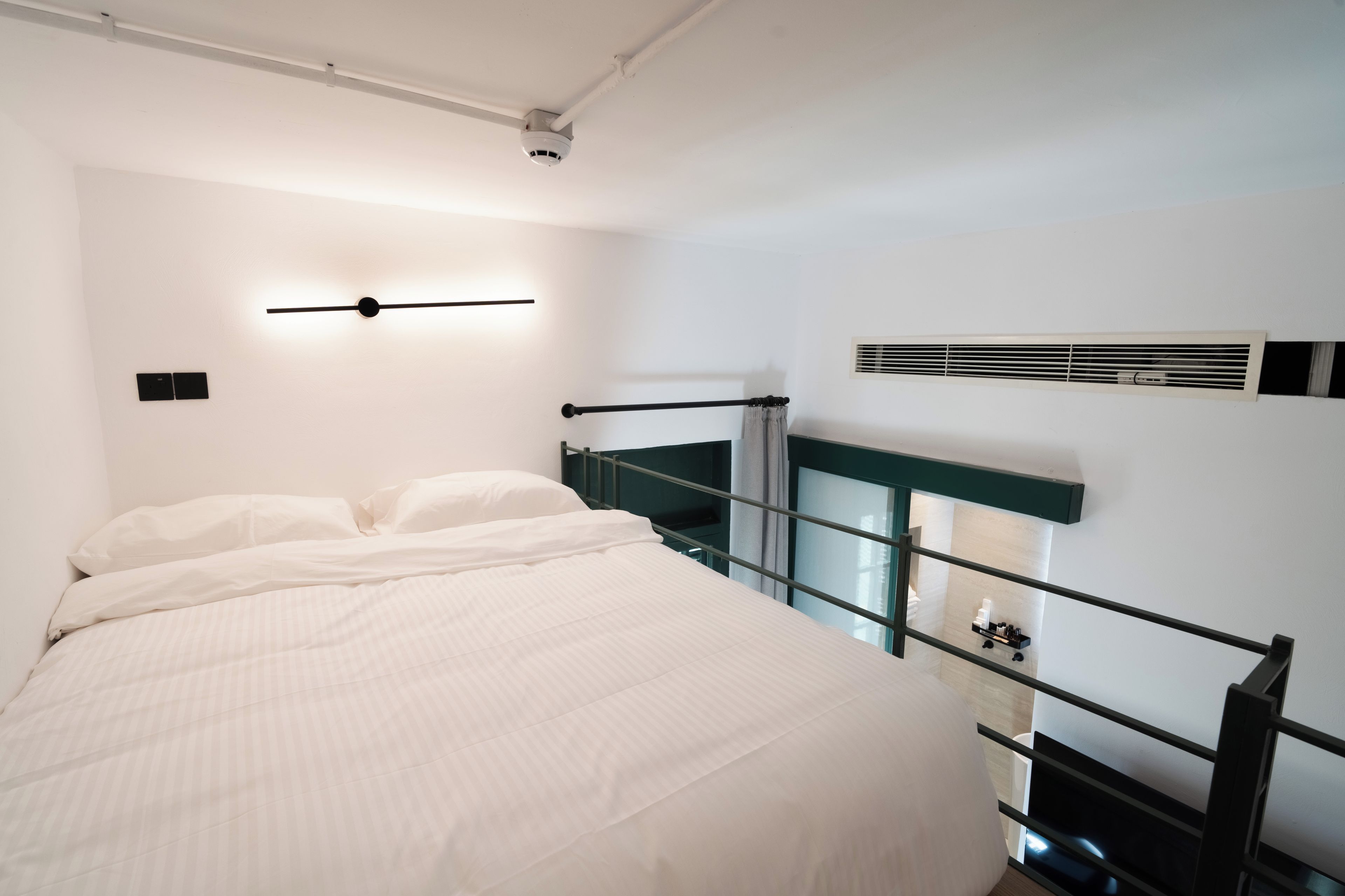 Een moderne hotelkamer met een bed, een wandlamp, een raam met uitzicht en een ingebouwde airconditioning.