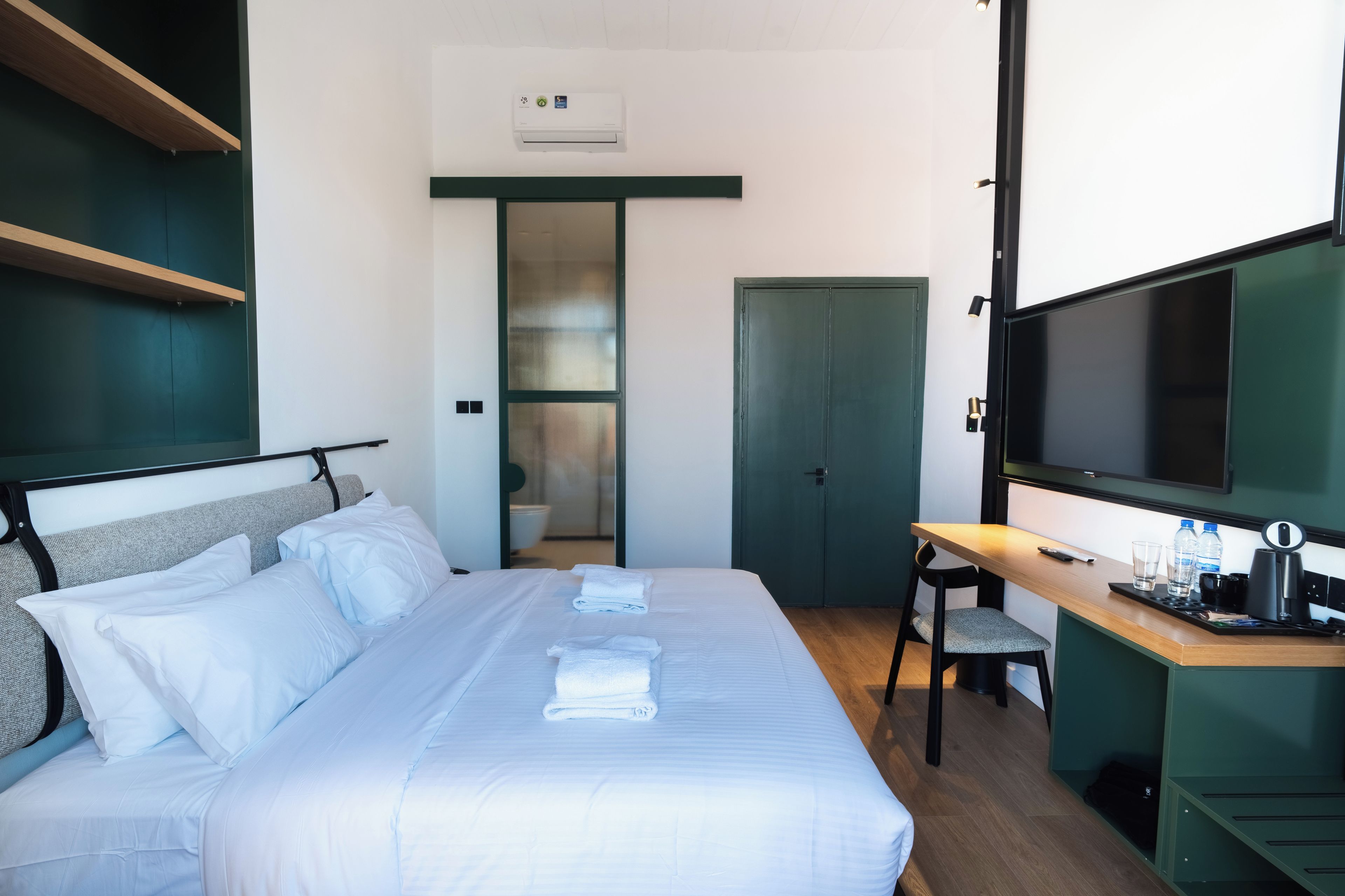 Ein Hotelzimmer mit Bett, Schreibtisch, Fernseher und Kleiderschrank.