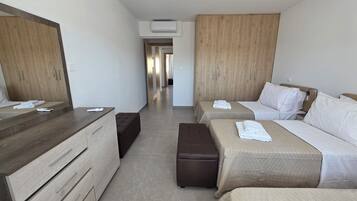 Habitación de hotel con dos camas, un armario de madera, un escritorio y un banco.