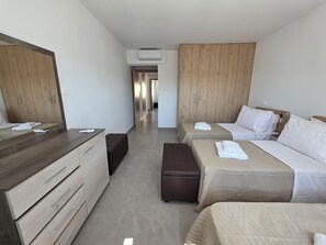 A hotel room with two beds, a wooden wardrobe, a desk, and a bench. - Kentrikon 1924 Boutique Hotel And Suites (Paphos)
