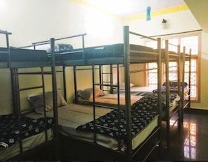 A dormitory room with bunk beds, a window with bars, and a small table. - Soloscape Stays Bengaluru (Bengaluru)