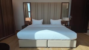 A large bed with a headboard, two bedside tables with lamps, and a mirror on the wall. - Samt Inn Al Narjis (Riyadh)