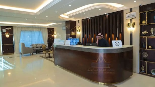 A reception area with a desk, a sofa, and a chandelier. - Samt Inn Al Narjis (Riyadh)