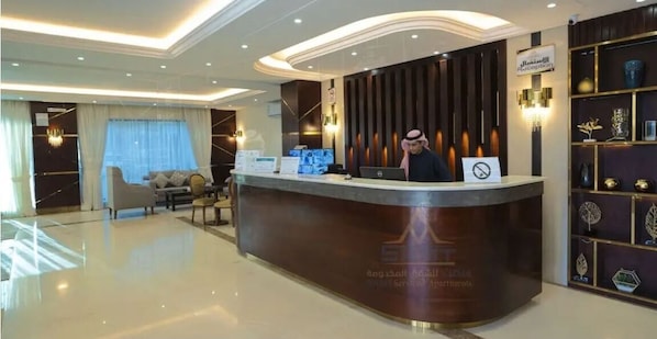 A reception area with a desk, a sofa, and a chandelier. - Samt Inn Al Narjis (Riyadh)