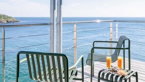 A deck with two chairs and a table, overlooking a body of water and a distant coastline. - Sainte-barbe Hotel Spa Le Conquet-mgallery Collect (Le Conquet)