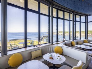 Un intérieur moderne avec de grandes fenêtres, des coins salon et des tables.