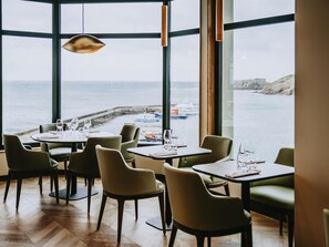 A restaurant with tables and chairs, large windows with a view of the sea and boats. - Sainte-barbe Hotel Spa Le Conquet-mgallery Collect (Le Conquet)