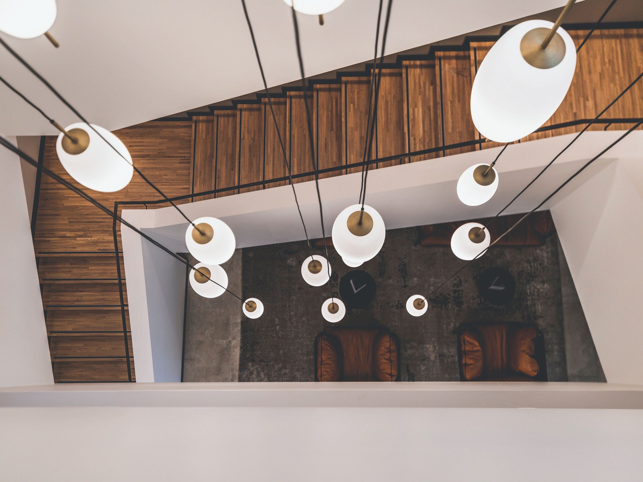 Un intérieur moderne avec des poutres en bois apparentes, un mur en béton et de nombreuses suspensions lumineuses.