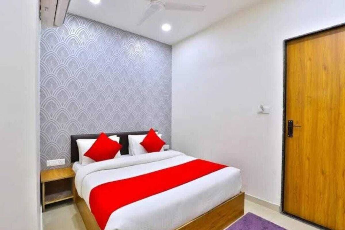 A bedroom with a bed, a wooden door, and a patterned wall.