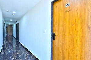 A hallway with a wooden door marked '205' and a marble floor. - Hotel Shivaay Motera (Ahmedabad)