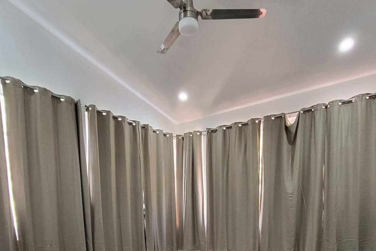 Ein Schlafzimmer mit zwei Betten, einem Deckenventilator und Vorhängen.