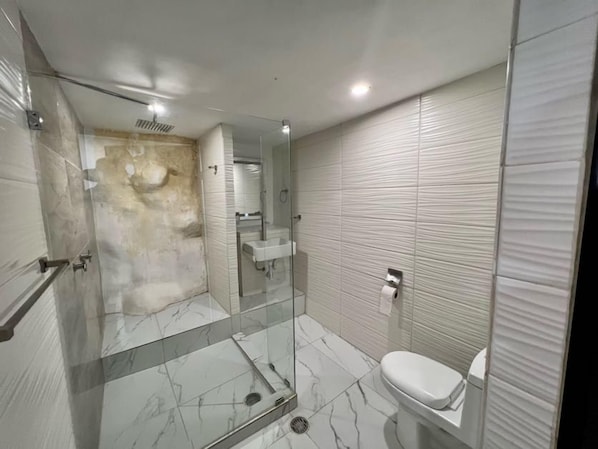 Ein modernes Badezimmer mit einer Duschkabine, einer weißen Toilette und einem Waschbecken.