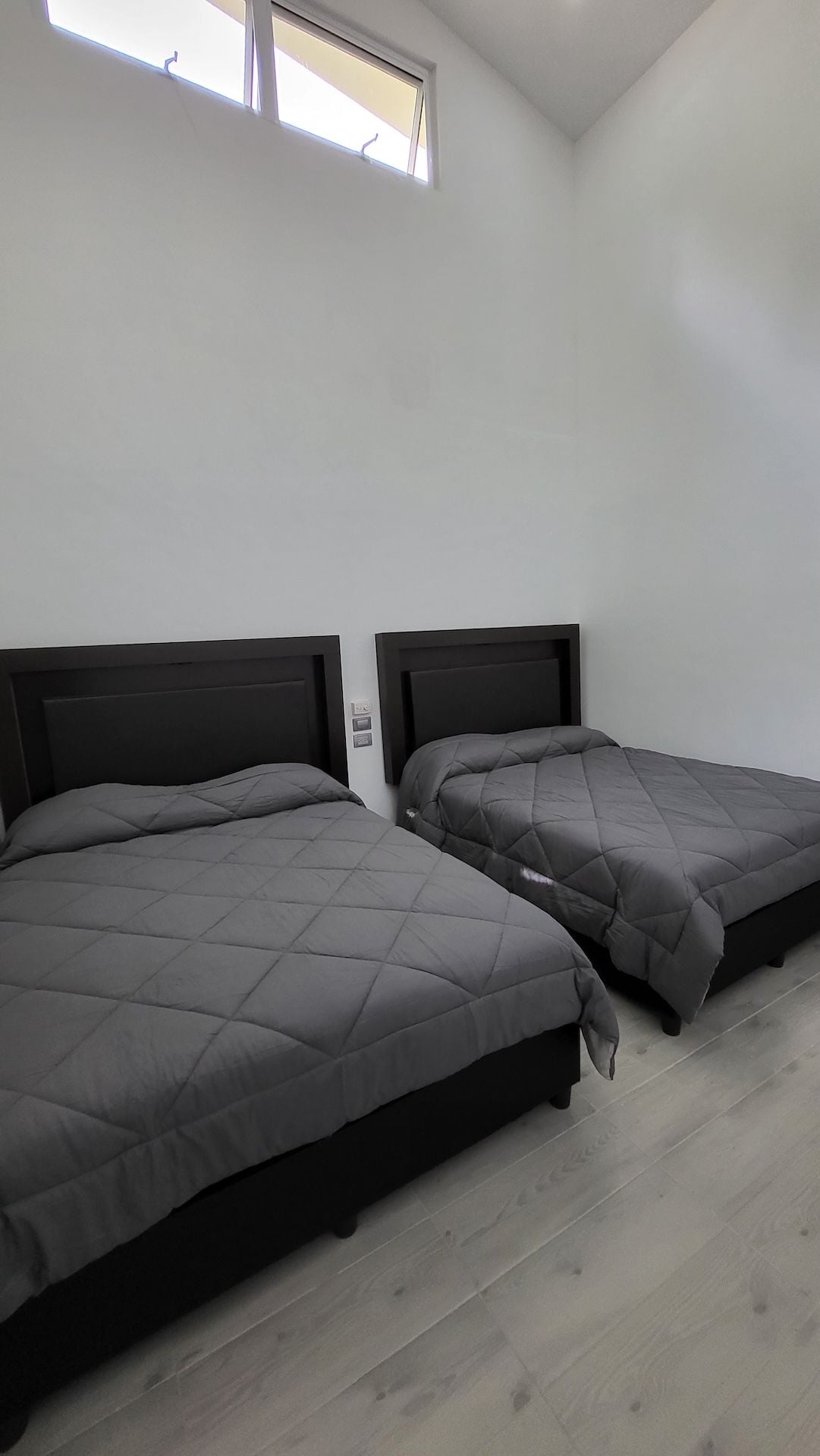 A room with two beds, a skylight, and a light-colored wooden floor.