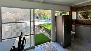 A kitchen with a refrigerator, a ceiling fan, and a view of a swimming pool.