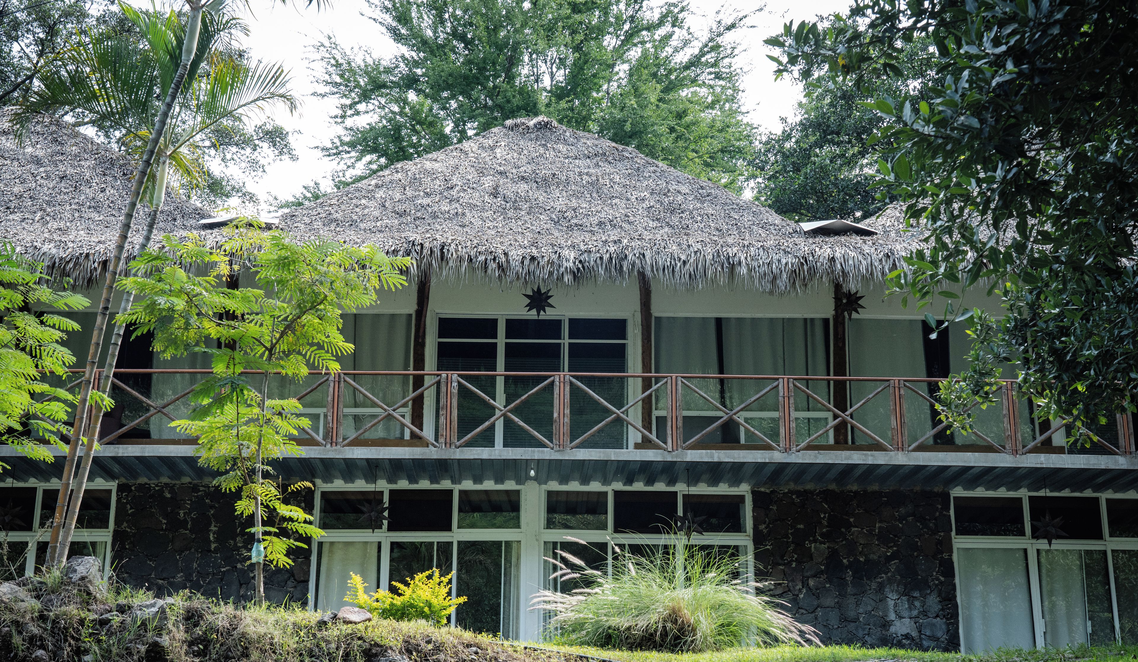 A two-story building with a thatched roof, a balcony with a wooden railing, and a star decoration above the windows.