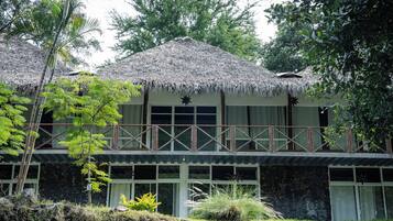 A two-story building with a thatched roof, a balcony with a wooden railing, and a star decoration above the windows.
