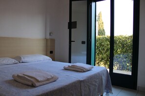 A bedroom with a bed, pillows, and a view through a glass door.