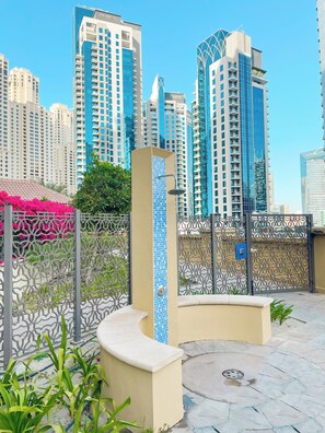 A modern urban setting with high-rise buildings, a decorative metal fence, and a tiled column. - JBR Rimal Apartments (Dubai)